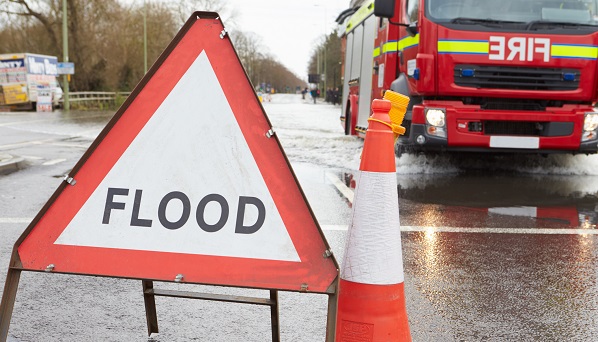 Flood warning sign in front of a fire engine