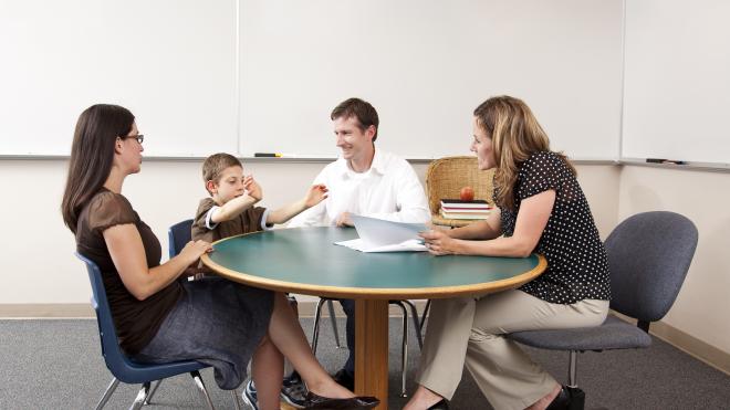 Teacher, social worker, foster carer and child sat around a table at PEP meeting