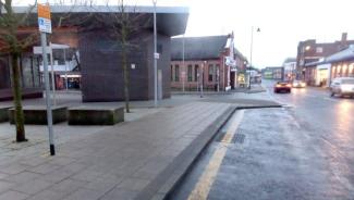 Road sign for parking condition on pavement with thick yellow line along carriageway edge.