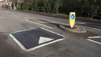 Speed bump next to a plastic bollard reminding drivers to keep left.