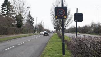 Vehicle activated sign on the side of road flashing 30 miles per hour speed limit.